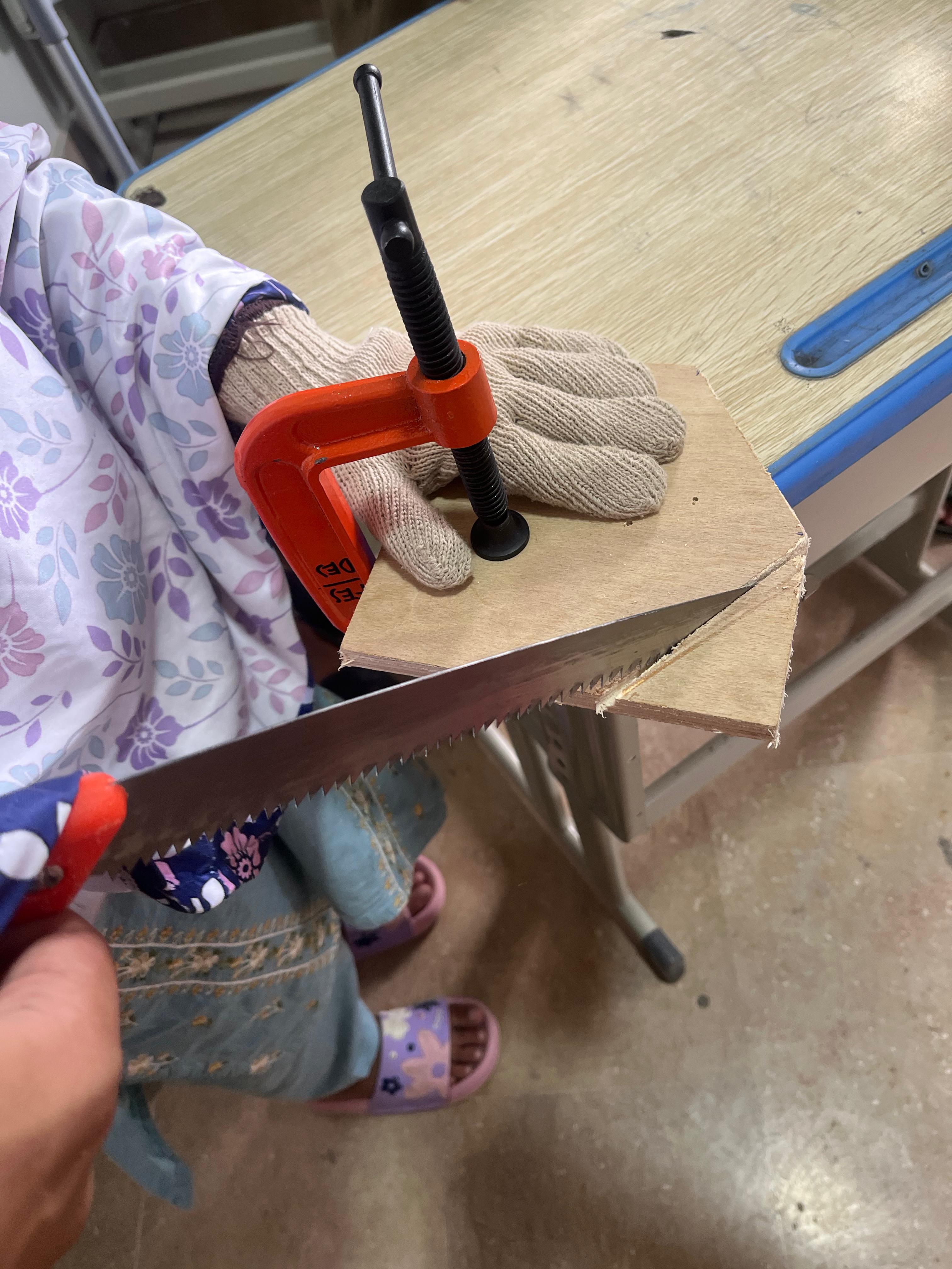 Young learner smiling and showing two thumbs up in classroom